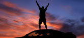 a man stands on a car and raises his fists skyward; CREDIT: iStock