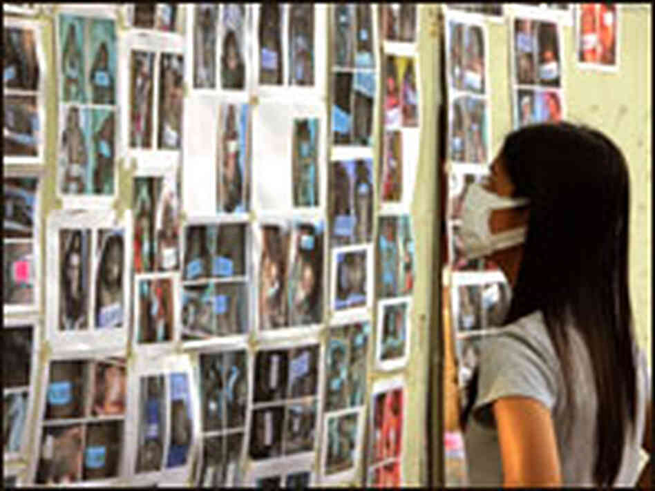 A Thai woman looks for a missing family member among dozens of victim photos. A Thai woman looks for a missing family member among dozens of victim photos.