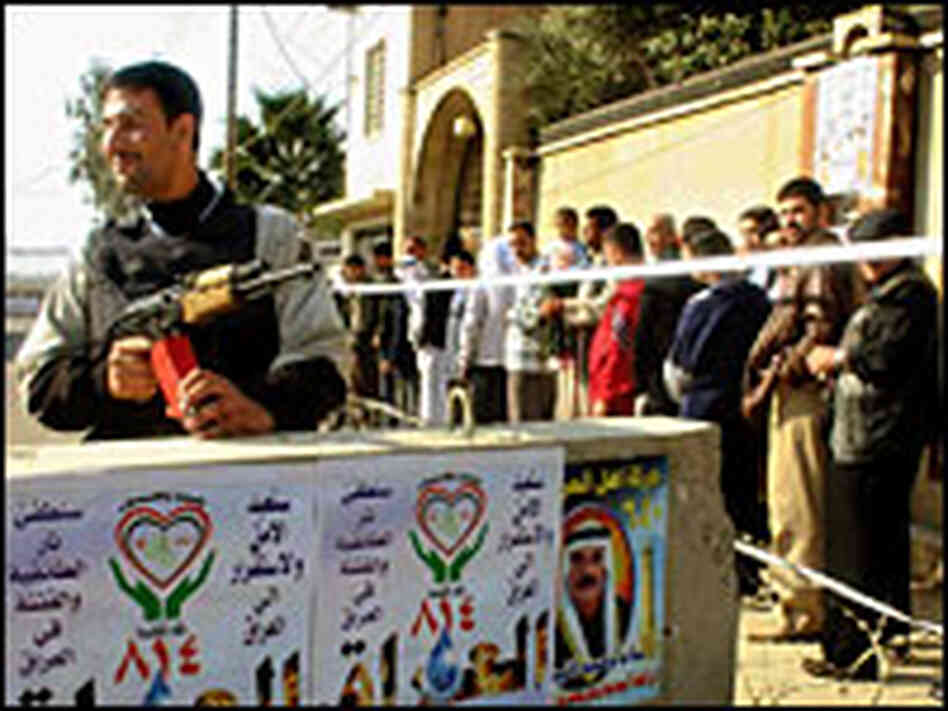 An Iraqi police commando guards a line of civilians waiting to cast their votes in Mosul An Iraqi police commando guards a line of civilians waiting to cast their votes in Mosul