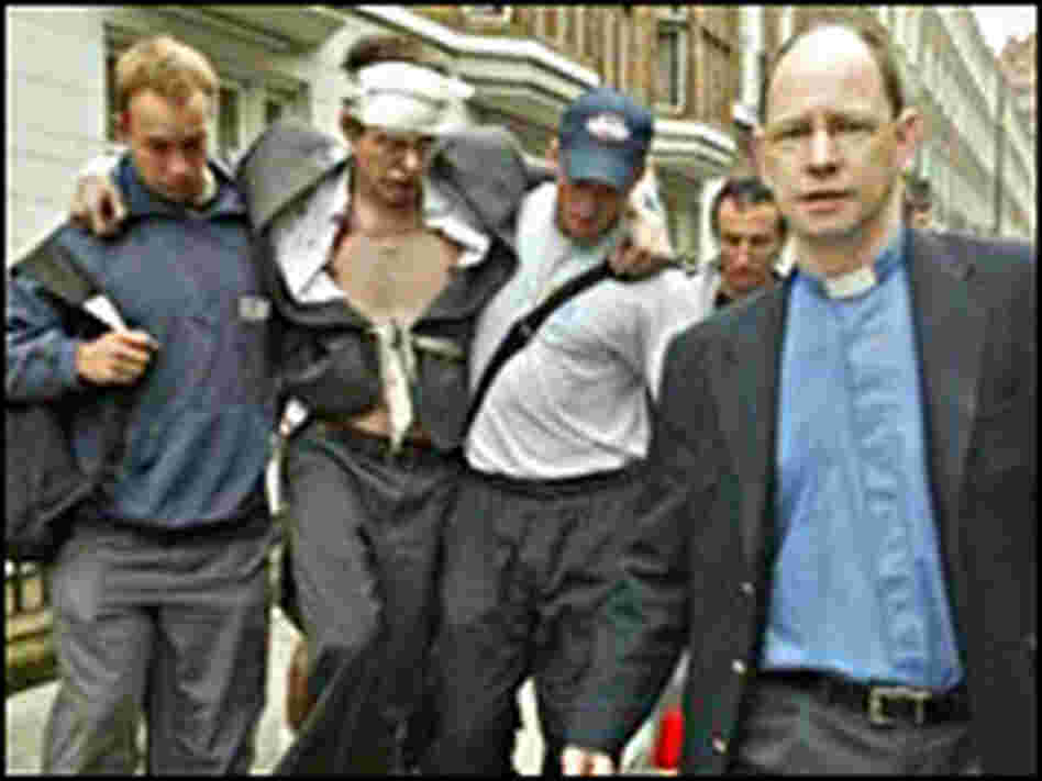 Rescuers help a man wounded near a London tube station in a series of attacks on the city's transi Rescuers help a man wounded near a London tube station in a series of attacks on the city's transi