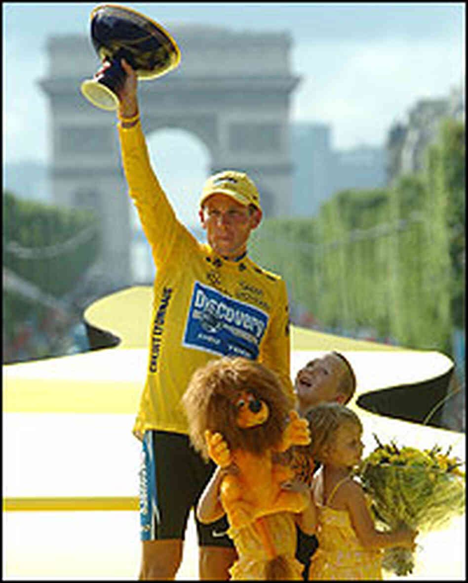 Lance Armstrong, with his three children at his feet, hoists Tour de France cup in victory. Lance Armstrong, with his three children at his feet, hoists Tour de France cup in victory.