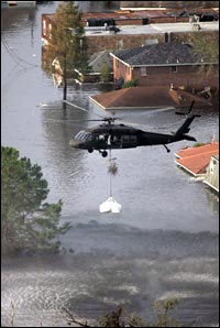 A helicopter drops sandbags to fill a broken section of a levee.