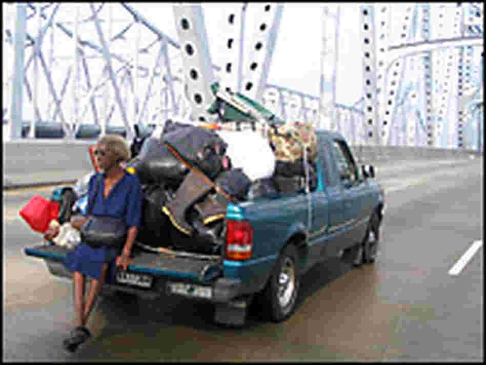 A woman sits on the back of a stranded pick up truck on a bridge. Credit: John Burnett, NPR.