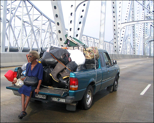 A woman sits on the back of a stranded pick up truck on a bridge. Credit: John Burnett, NPR.