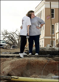 Laurie Johnson and Lisa Wilburn hug amid debris and damage.