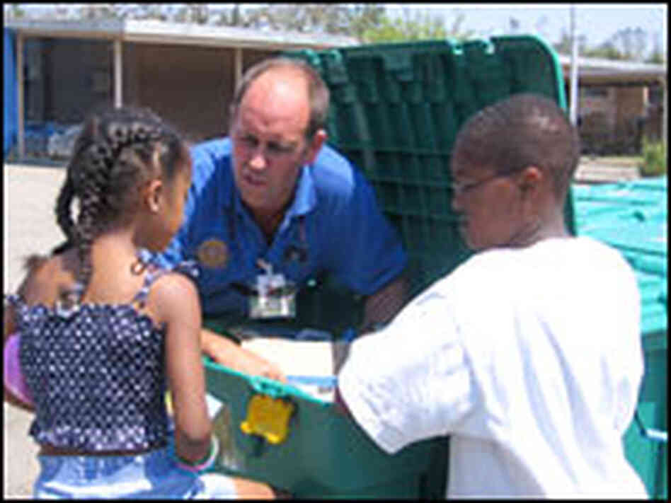 Volunteer John Green shows the contents of a "shelter box" to Donald and Danielle Vince.