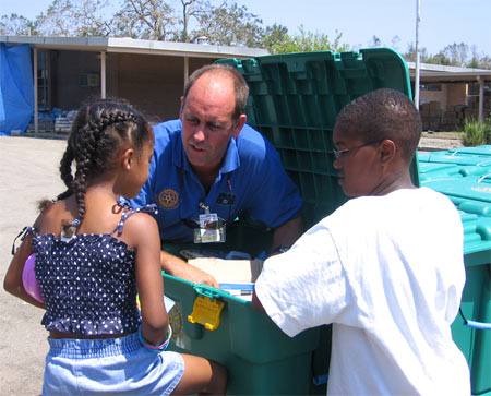 Volunteer John Green shows the contents of a "shelter box" to Donald and Danielle Vince.