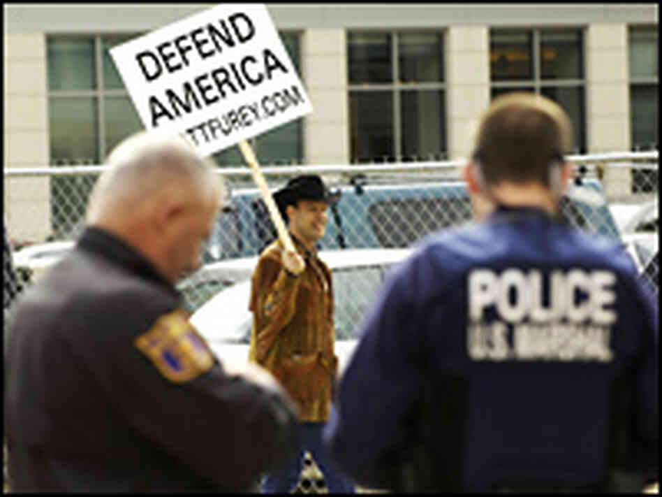 A lone protestor carries a placard while shouting "defend America from the terrorists". A lone protestor carries a placard while shouting "defend America from the terrorists".