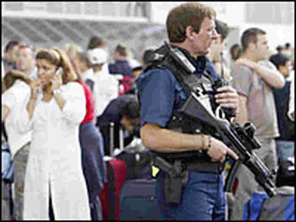 A policeman secures the area as passengers wait at Heathrow airport in London.