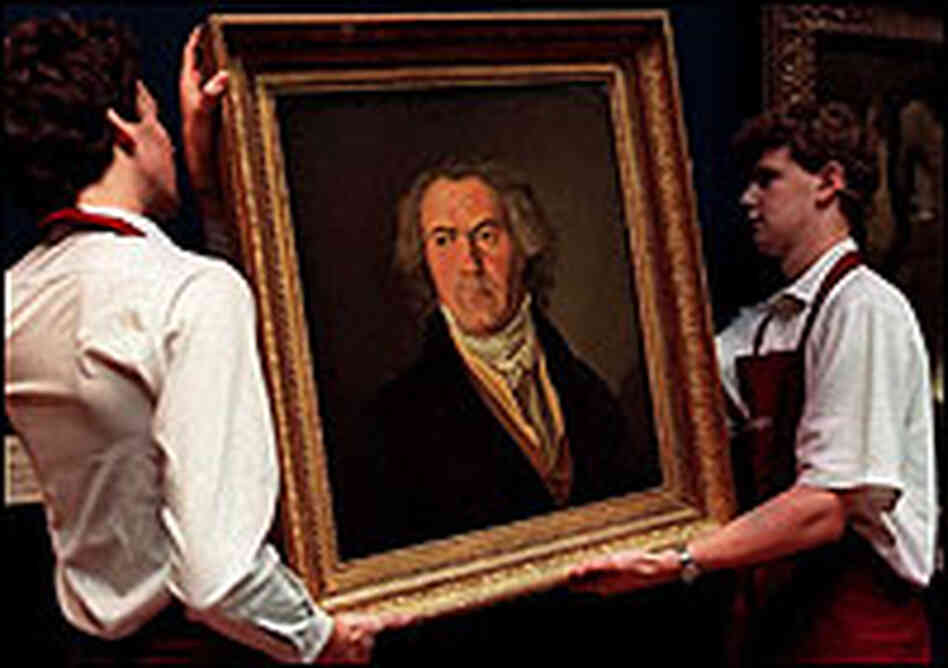 Two workmen carry a portrait of Ludwig von Beethoven.