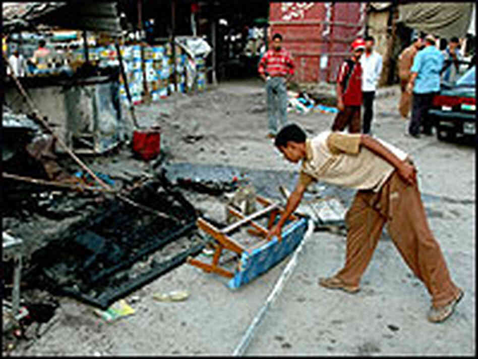 An Iraqi man picks up a bench by a destroyed market stall in the town of Mahmoudiyah An Iraqi man picks up a bench by a destroyed market stall in the town of Mahmoudiyah