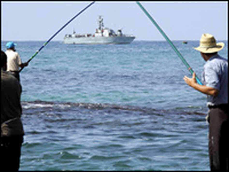 Israelis men fish while an Israeli gunboat patrols off the northern Israeli coast. Israelis men fish while an Israeli gunboat patrols off the northern Israeli coast.