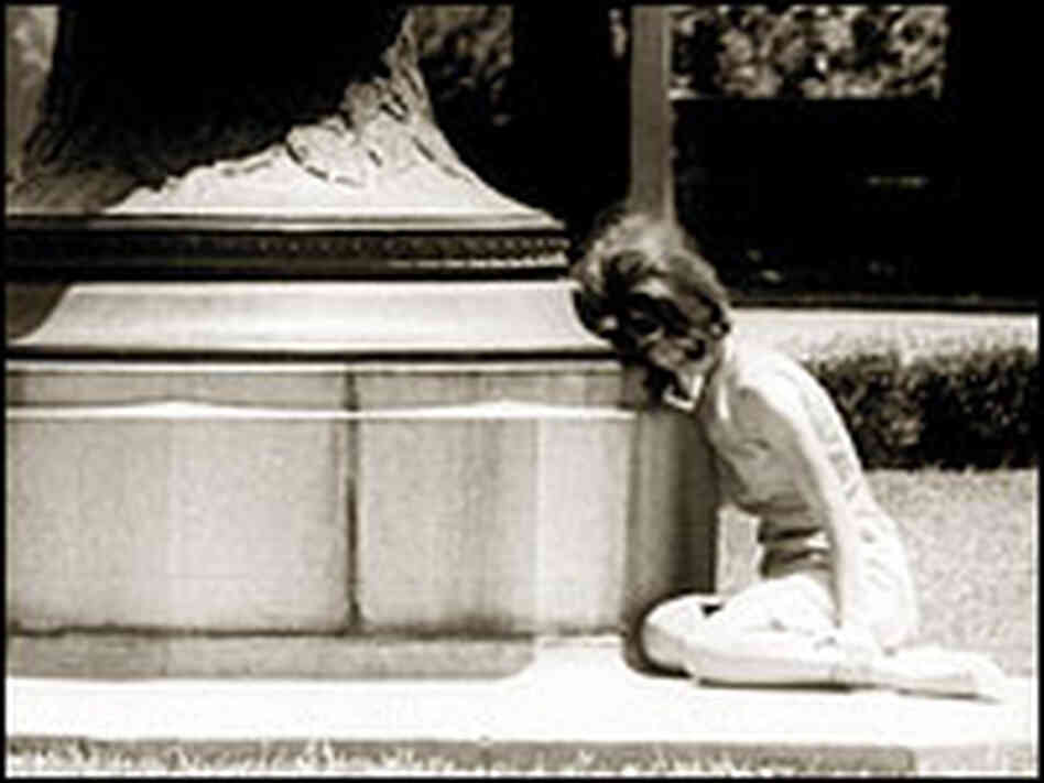 A woman cowers in fear behind a statue during a shooting incident at the University of Texas in 1966