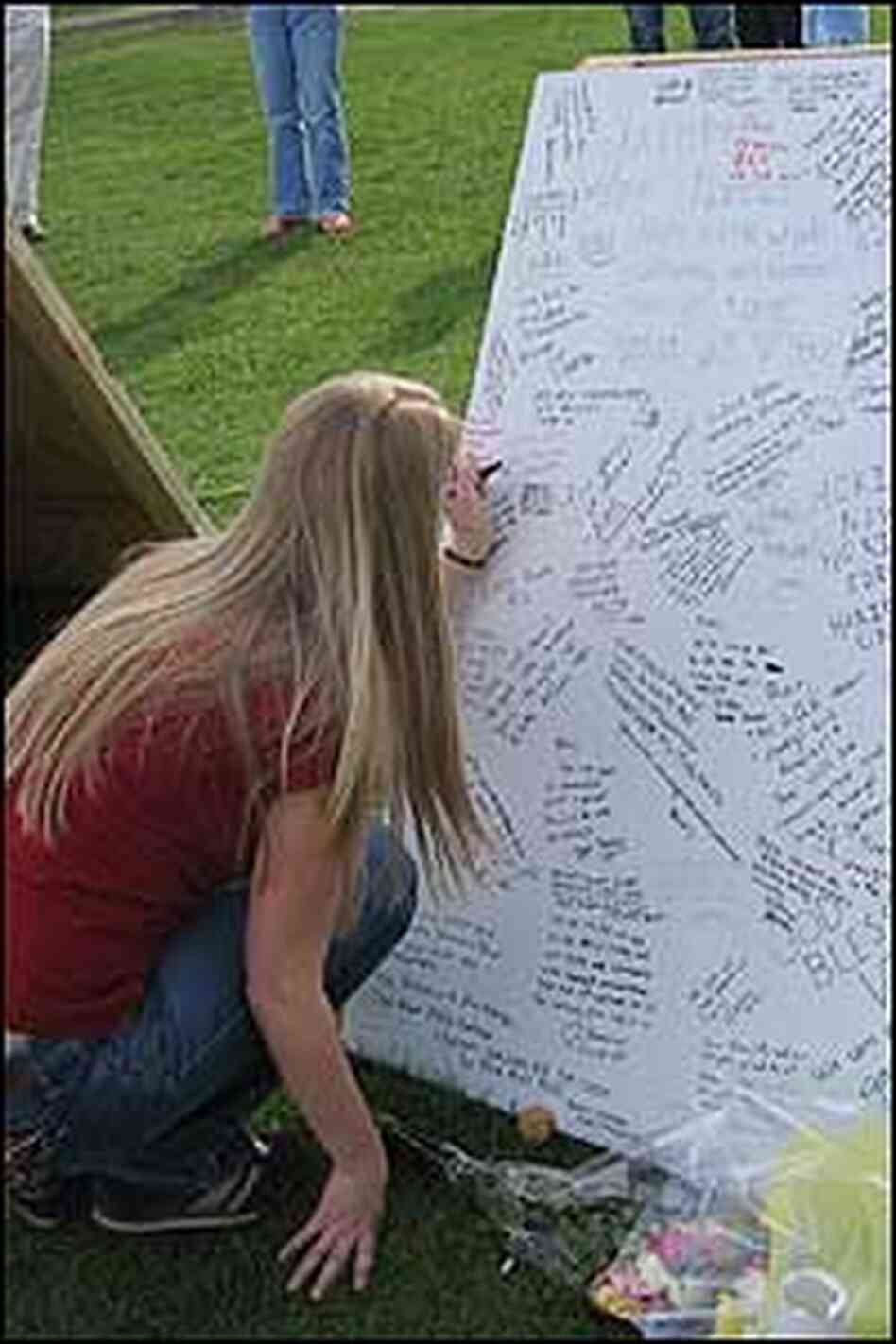Memorial boards stand outside Norris Hall at Virginia Tech. A woman records her thoughts. Memorial boards stand outside Norris Hall at Virginia Tech. A woman records her thoughts.