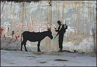 Banksy depicts an Israeli soldier checking the ID of a donkey in another image on the barrier wall.