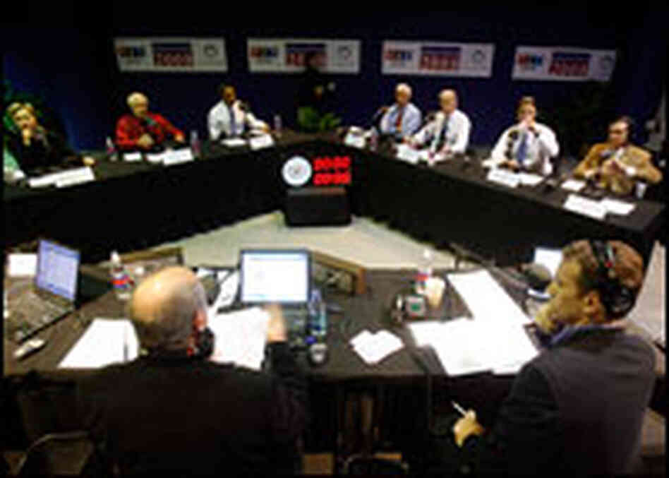The Democratic presidential candidates sit around a V-shaped table during a radio debate in Iowa