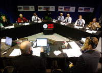 The Democratic presidential candidates sit around a V-shaped table during a radio debate in Iowa