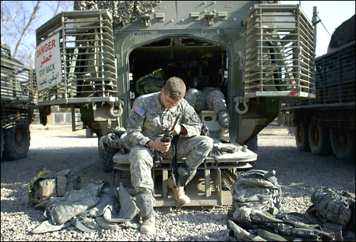 A U.S. soldier from the 5-20 Infantry Division cleans his rifle on the ramp of his Striker.