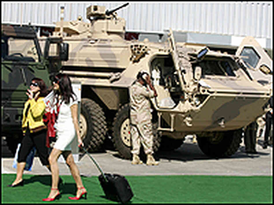 Two women walk past tanks as they attend the opening of the IDEX exhibition in Abu Dhabi.