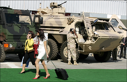 Two women walk past tanks as they attend the opening of the IDEX exhibition in Abu Dhabi.