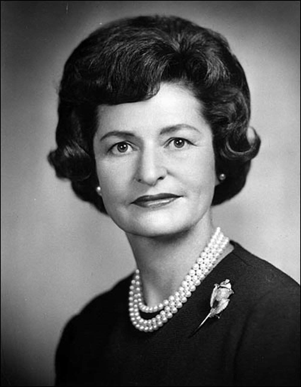Headshot of Lady Bird Johnson wearing a pearl necklace and a brooch