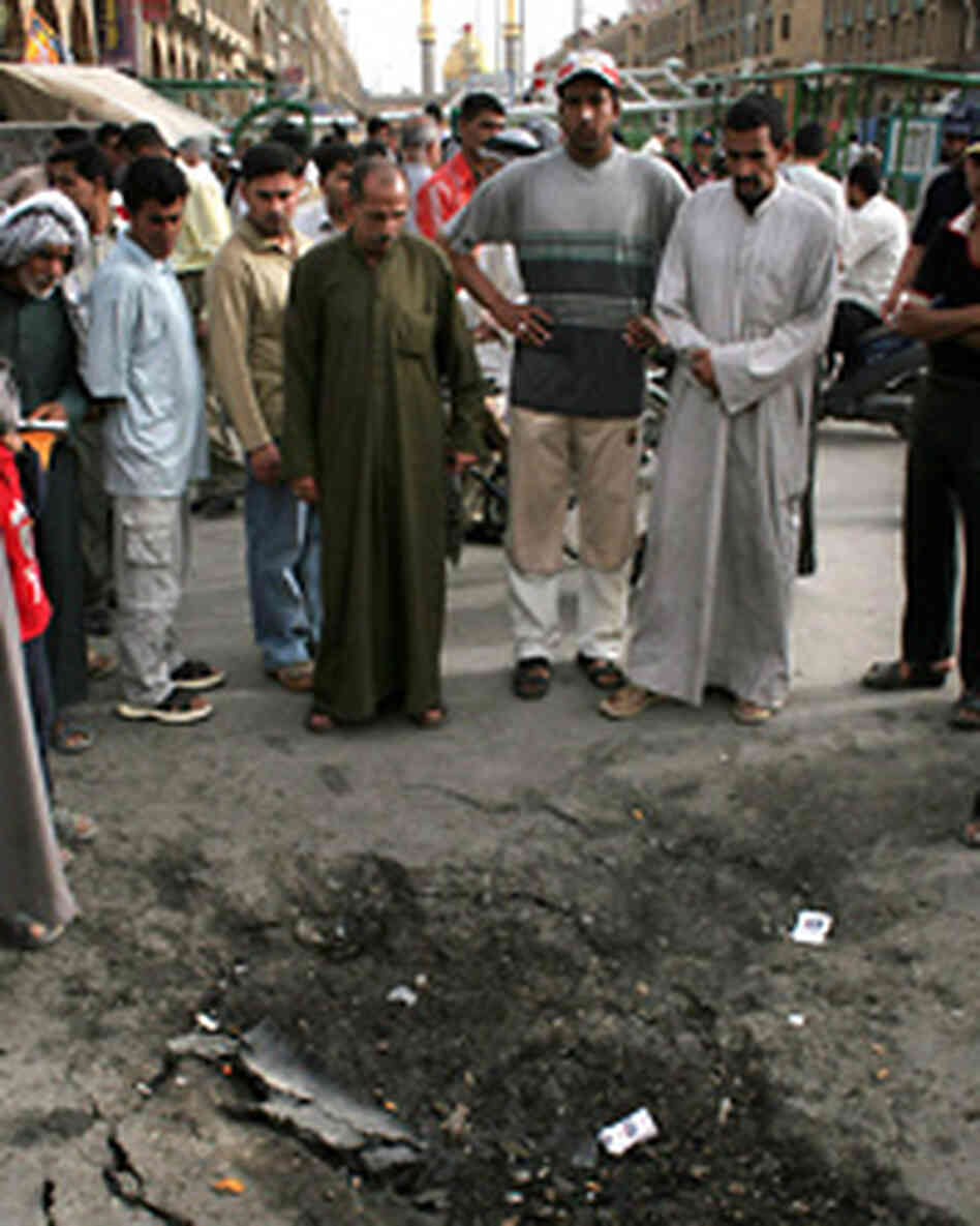 Iraqis inspect a crater left by an explosion at the site of a suicide car bomb attack Iraqis inspect a crater left by an explosion at the site of a suicide car bomb attack