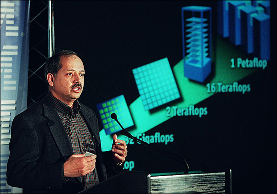 IBM executive stands before a graphic explaining BlueGene computer's power.
