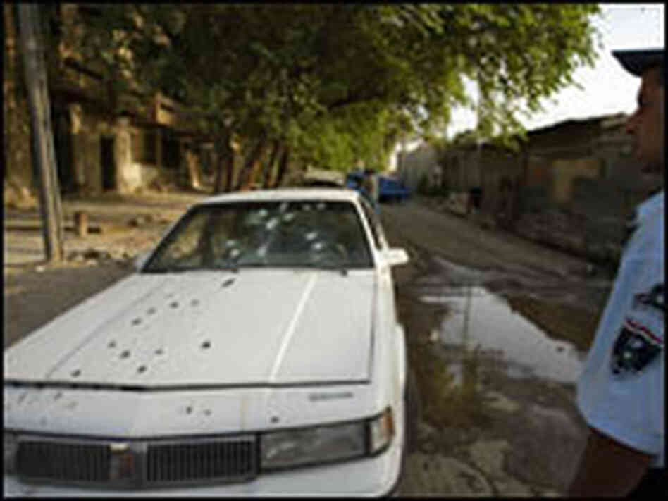 An Iraqi policeman stands by a bullet-riddled car of two women allegedly shot dead by guards.