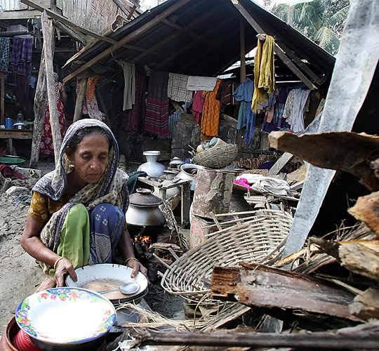 A woman prepares food in front of her destroyed house on the south coast of Bangladesh on Sunday.