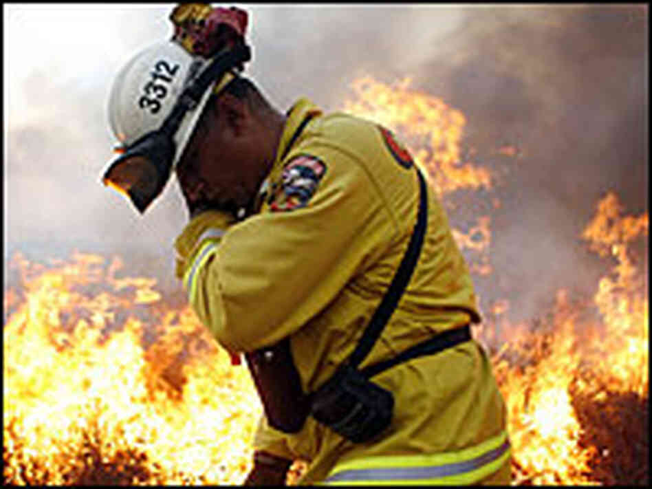 A firefighter lights backfires to protect the neighborhood of Bonita in San Diego, Calif.,