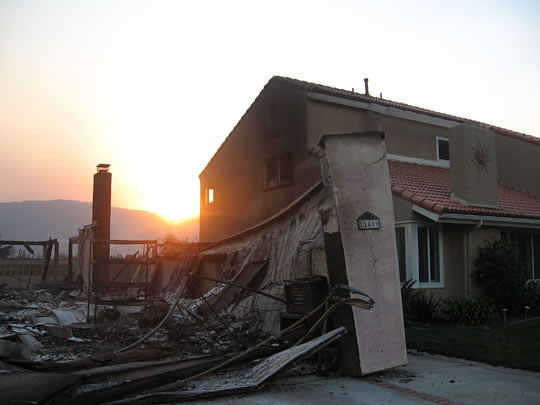 A wildfire claimed a house in the town of Poway while sparing the residence next door.