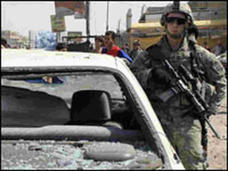A U.S. soldier stands guard at the site of a car bomb attack in Baghdad on Monday.