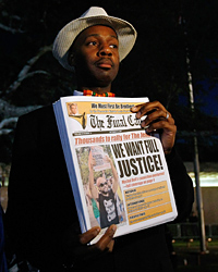 A man holds a newspaper before the start of a civil rights march in Jena, La., Thursday.
