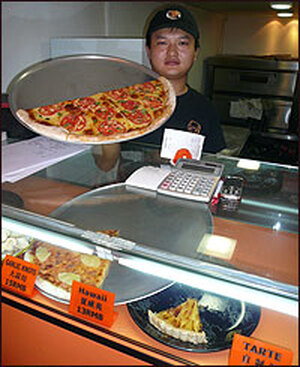 A shopkeeper displays his wares at Shanghai's "New York Pizza Parlor." The shop sells around 50 large pizzas every day; the increasing popularity of Western food means China's 1.3 billion residents are consuming more milk than before.