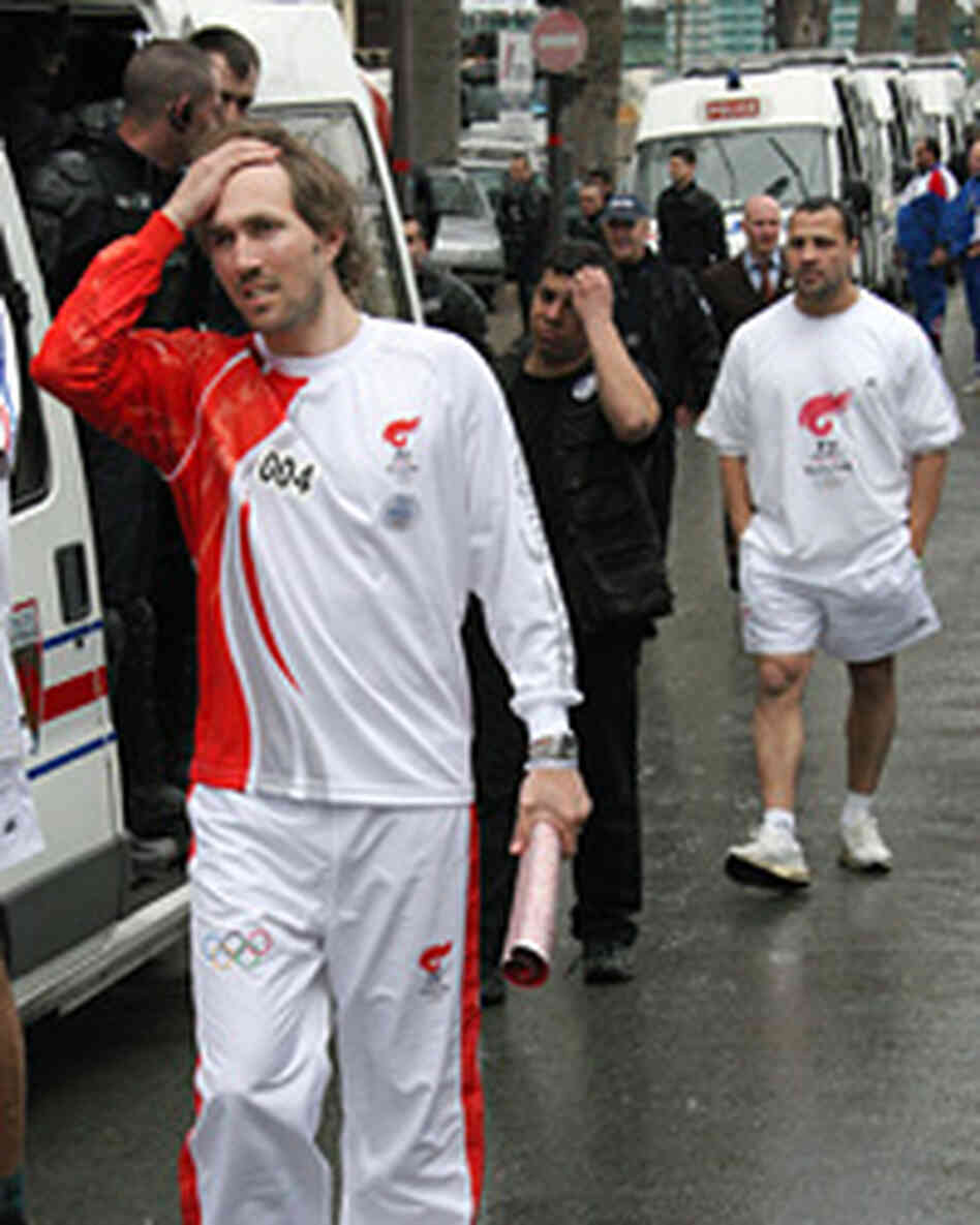 French former tennis player Arnaud Di Pasquale reacts as he carries an extinguished torch. French former tennis player Arnaud Di Pasquale reacts as he carries an extinguished torch.