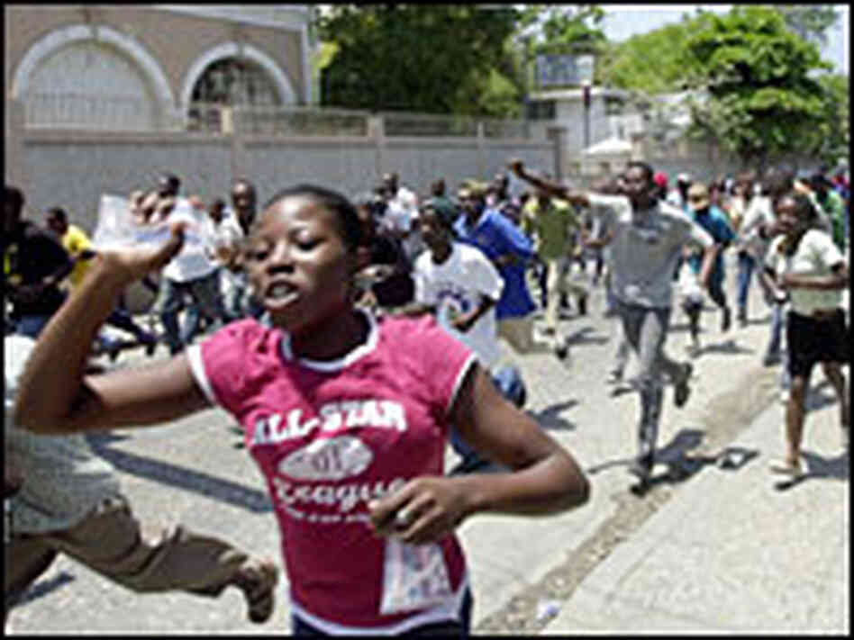 Haitians run through the streets in Port-au-Prince during protests against the rising cost of living