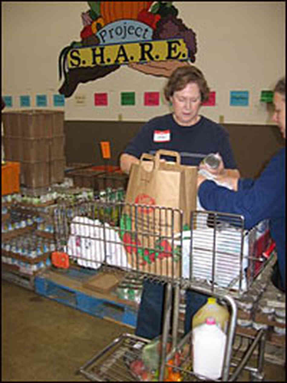 Volunteer hands out canned food at Project Share Volunteer hands out canned food at Project Share