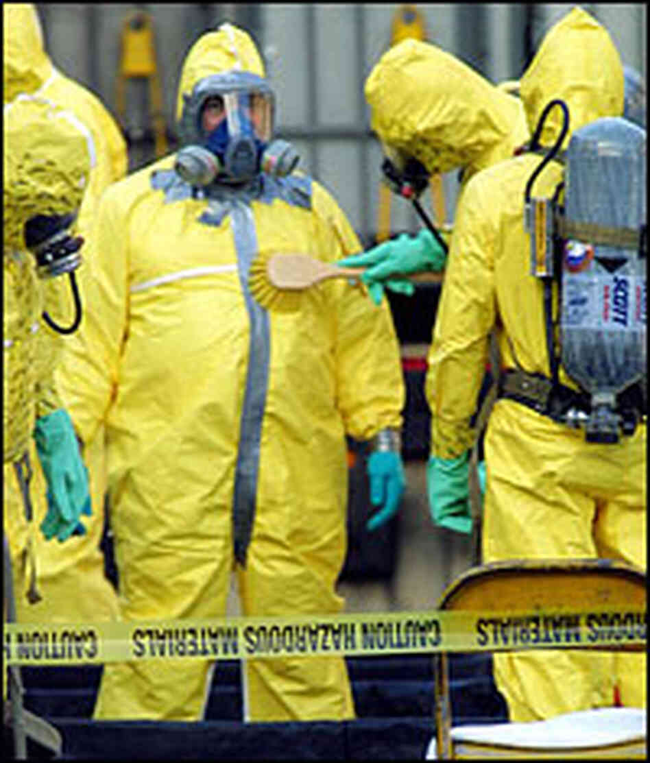 A hazmat response team member uses a brush to decontaminate a colleague in 2001.