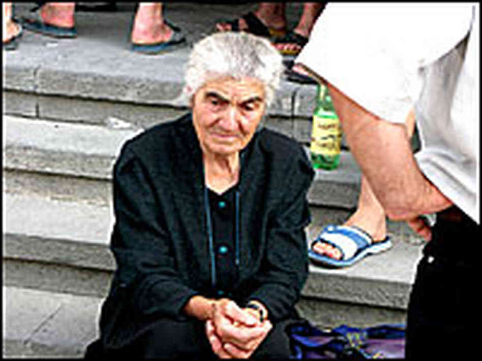 An elderly woman waits on the steps of Gori City Hall.