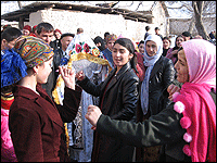Tajik girls dance to the music as a government monitor watches.