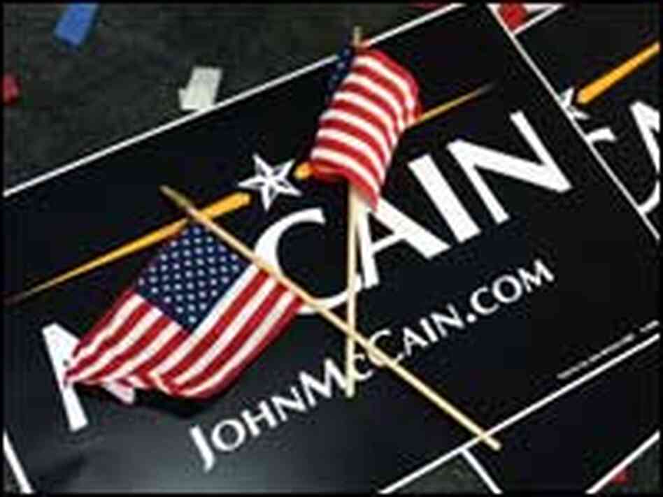 Two campaign posters for John McCain are covered by a pair of flags Two campaign posters for John McCain are covered by a pair of flags