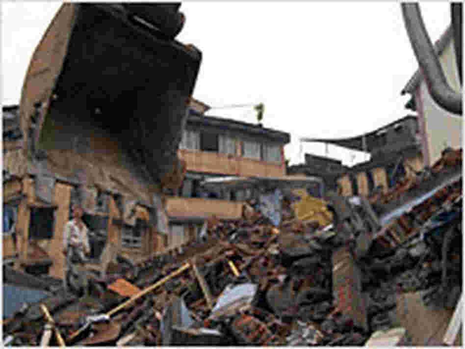 Wang Wei stands atop the rubble of his parents' apartment building in Dujiangyan, China.