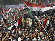 Thousands of followers of Shiite cleric Muqtada al-Sadr, pictured in the poster, converge on Firdous Square in central Baghdad, Iraq for a mass prayer to protest a proposed U.S.-Iraqi security pact on Friday, Nov. 21, 2008. Khalid Mohammed/AP

