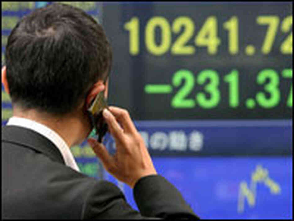 A man looks at an electronic board displaying the sharp drop in stock prices in Tokyo.