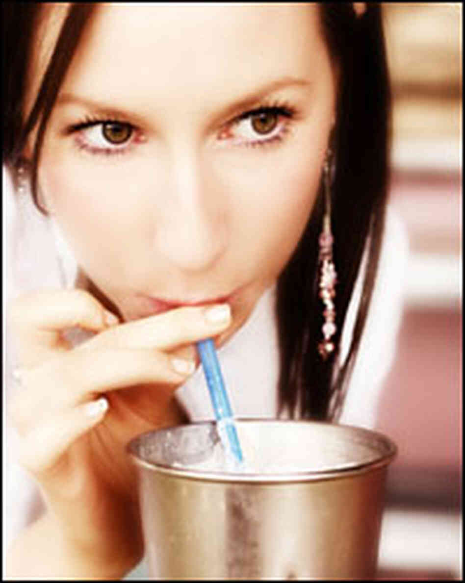 A woman savors a milkshake.