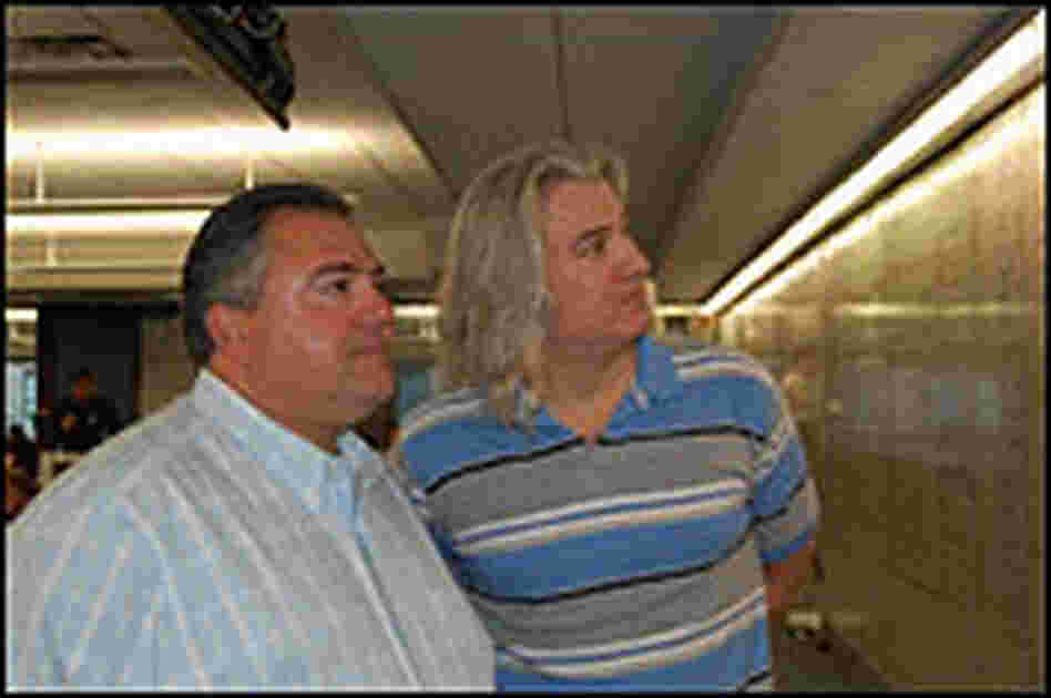 Thomas S. Corona (left) and Will Aston-Reese look at the white board on their trading floor.