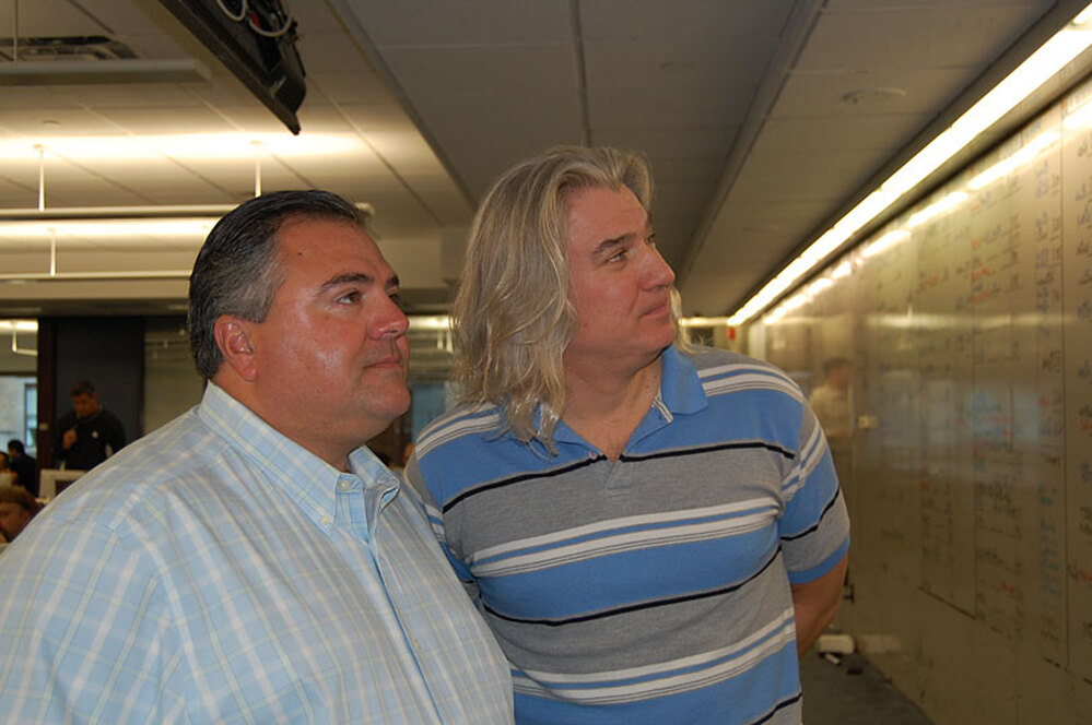 Thomas S. Corona (left) and Will Aston-Reese look at the white board on their trading floor.