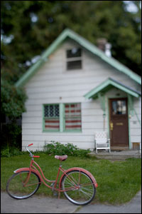 A faded red bicycle parked in a yard.