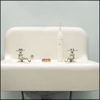 A set of dentures with pink gums lying on a vintage white porcelain sink.