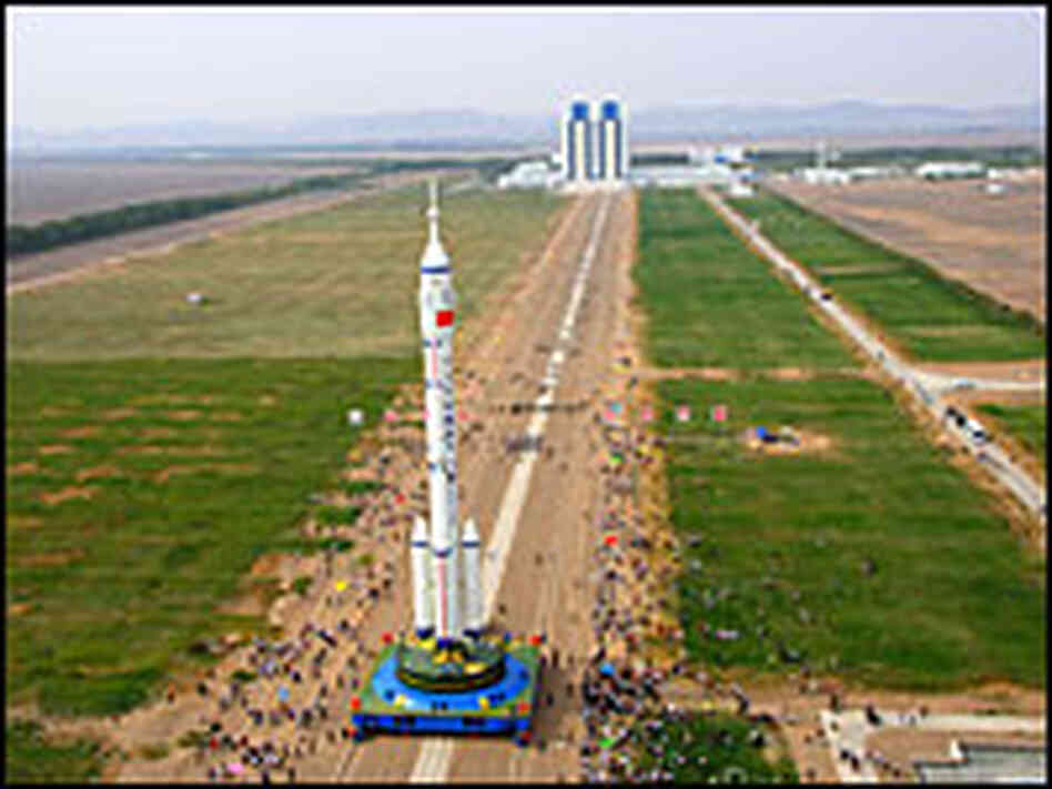 Workers move a rocket carrying China's manned spacecraft from the assembly plant to a launch pad.